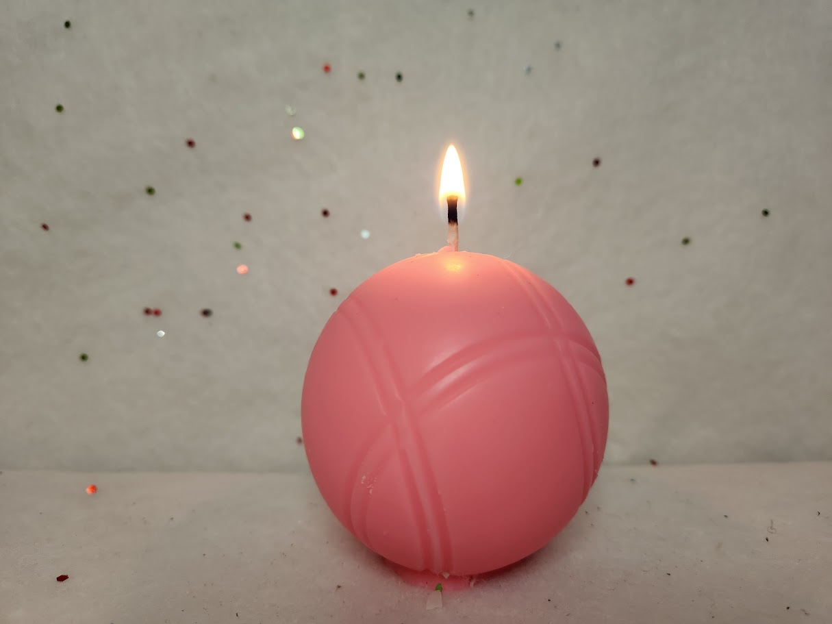 Bougie boule de pétanque rose fluo allumée bougie boule pétanque rose