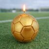 Bougie ballon de football dorée allumée de 8 cm posée sur un terrain de foot