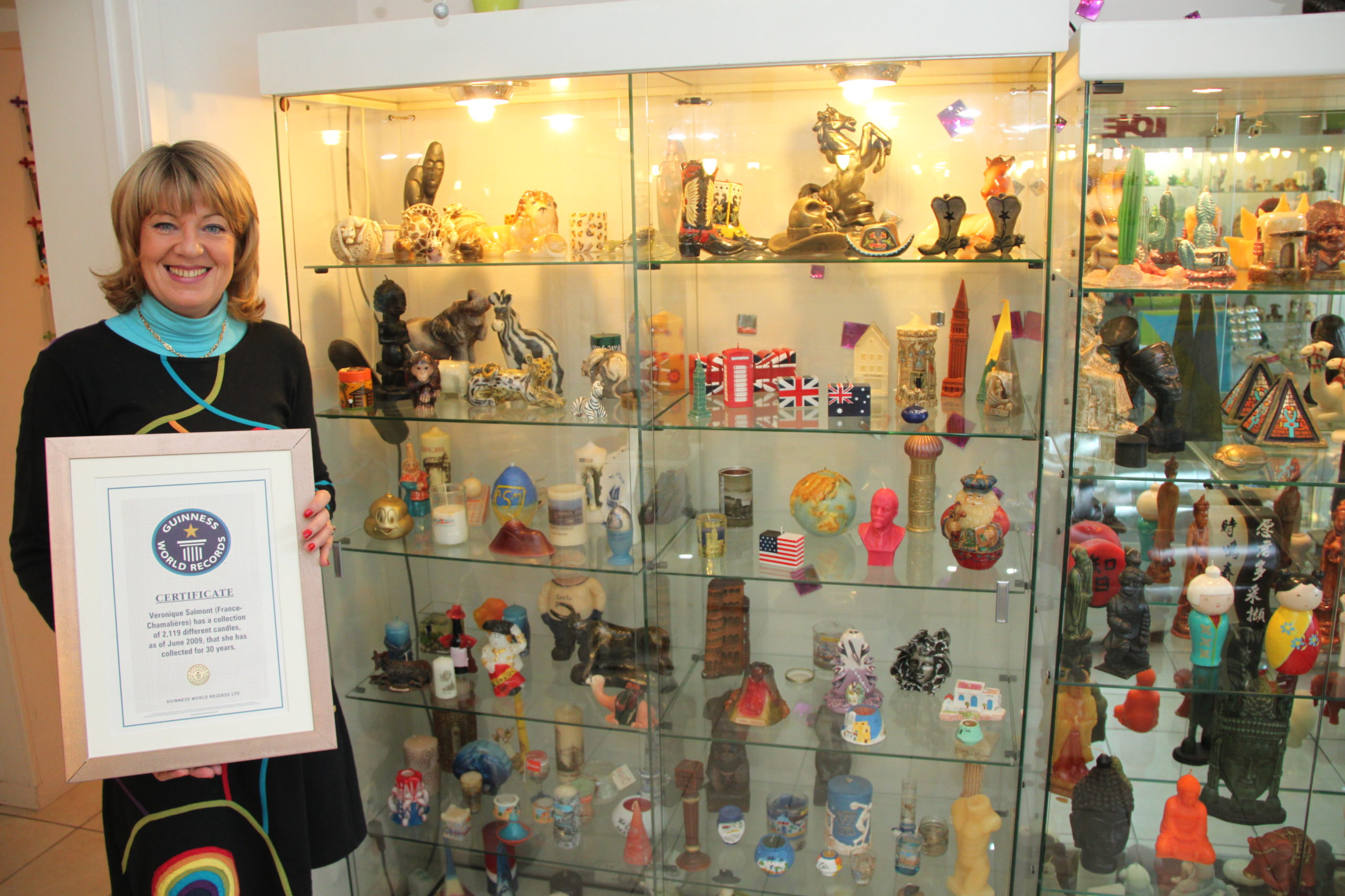 Véronique Salmont, créatrice de La Fée des Bougies à Cestas, tenant son diplôme du Guinness World Records devant sa collection
